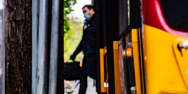 Man wearing face mask stepping off a bus